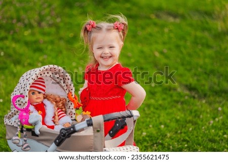 a child with a toy stroller and a doll is playing in nature