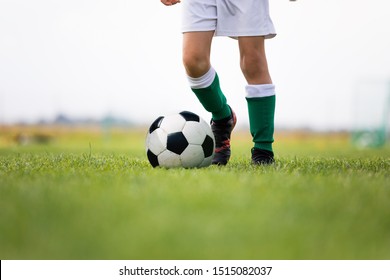 Child Training Soccer On Fresh Grass Pitch. Soccer Camp For Kids. Boys Practice Dribbling In A Field. Player Develop Dribbling Skills. Boy In Yellow Shirt Training With Ball