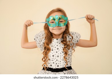 The child tries on carnival masquerade masks.  Little cute girl getting ready for carnival party, masquerade - Powered by Shutterstock