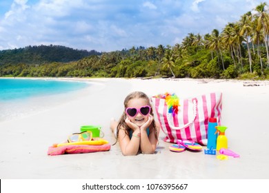 Child At Tropical Beach With Bag And Toys. Little Girl Playing With Water And Sand Toy Bucket. Beach Bag With Swimming And Snorkeling Accessories For Family Summer Vacation At Ocean Shore. Kids Play.