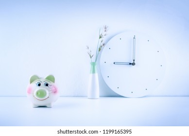 Child Trust Fund / Children Savings Habits, Family Finance Concept : Smiling Piggy Bank On A Working Desk, Office Table With A Clock, Depicts Money Savings For Kids Or Juniors, White And Light Theme 