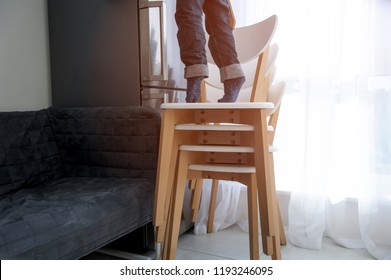 Child Trying To Reach Food On The Refrigerate In The Kitchen. Addicted Kid. Child Make Top From Chairs And Climb Up