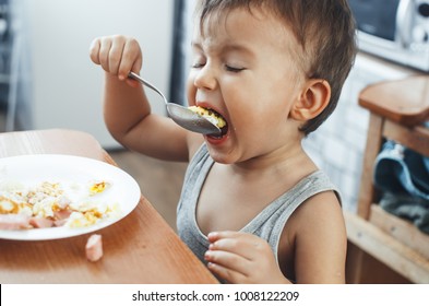 Child T-shirt In The Kitchen Eating Scrambled Eggs, With A Spoon