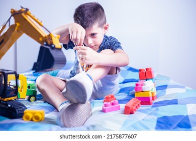 child tying shoes with hands on bed in his room among the toys - Powered by Shutterstock