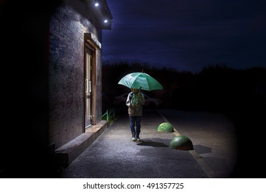 Child With An Umbrella In The Dark. Boy Walking Down The Street At Night. Empty Space For Your Text