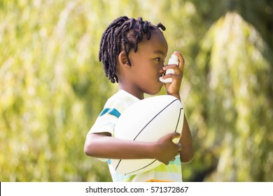 Child Is Using An Asthma Inhaler In Park