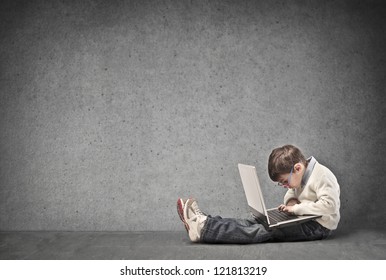 Child using a laptop computer with a dark white background