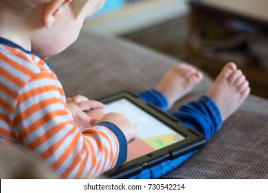 Child Using A Touch Screen Tablet To Play Learning Game