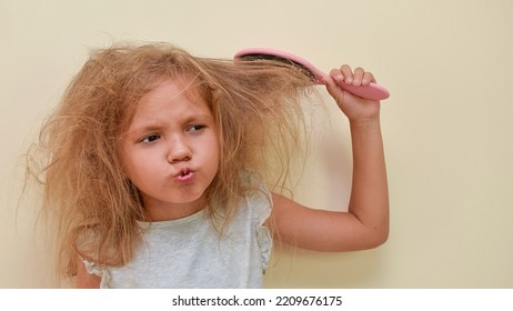 A Child With Very Tangled Hair Is Trying To Comb His Hair. A Little Girl's Hair Is Hard To Comb, Disheveled And With Tangles After Washing. Hair Does Not Comb Without A Conditioner Balm.