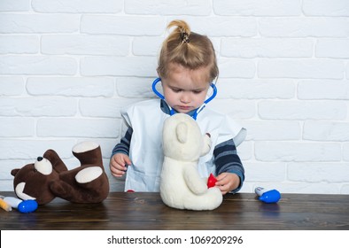 Child veterinarian with stethoscope examine toy animals. Future profession concept. Boy play doctor with teddy bears on white wall. Health, healthcare, medicine. Game, development, imagination.