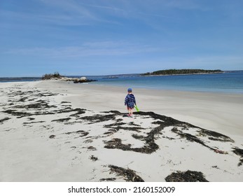 A Child Walking Alone Along A Sandy Beach.