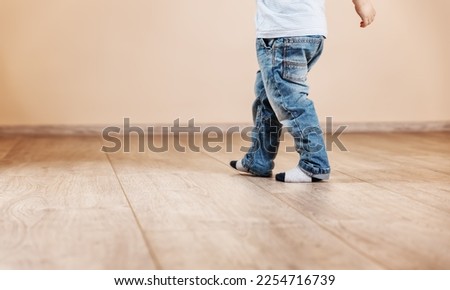 Child walking along the living room. Concept of the new house and control warming in the house.