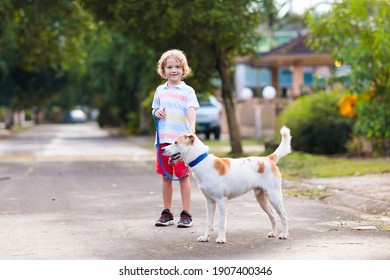 Child Walking Dog. Kid Playing With Cute Puppy. Little Boy Running With His Pet. Children Play In Suburban Neighborhood Street. Animal Friends. Friendship And Love.