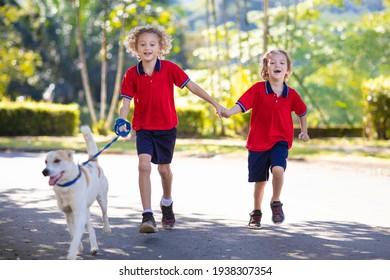 Child Walking Dog. Kid Playing With Cute Puppy. Little Boy Running With His Pet. Children Play In Suburban Neighborhood Street. Animal Friends. Friendship And Love.