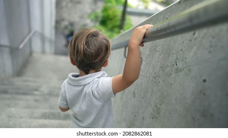 Child walking down stairs holding handrail