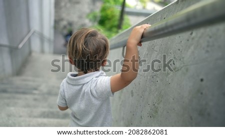 Child walking down stairs holding handrail