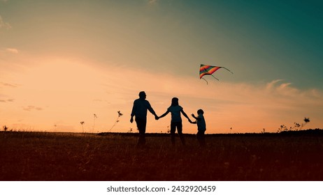 Child wants to fly kite. Happy family with child in park playing with kite. Young family is playing with kite in meadow. Family walk on grass, child dreams of flying. Dad mom son play travel in nature - Powered by Shutterstock