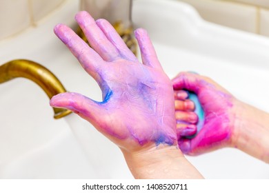 child washes his hands from bright paint after drawing.  paint hands after drawing class