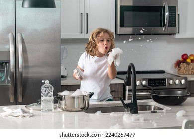 Child washing dishes near sink in kitchen. Child with sponge with dish washing liquid is doing the dishes at home kitchen by using wash sponge and dish washing. - Powered by Shutterstock