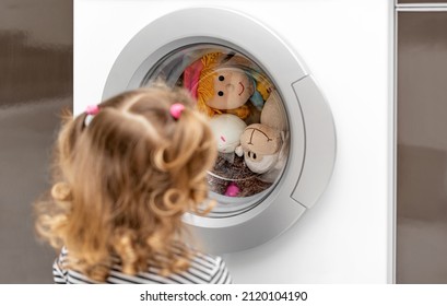 The Child Watches As The Washing Machine Washes Toys.