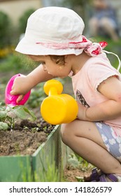 Child With A Watering Can In A Garden