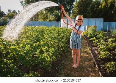 Child watering plants garden. Kid with water hose sunny backyard girl gardening Summer outdoor holidays village. Children Farmer help parents sunset authentic, candid, green living, eco friendly - Powered by Shutterstock