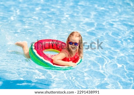 Child with watermelon inflatable ring in swimming pool. Little girl learning to swim in outdoor pool of tropical resort. Kid eye wear. Water toys and floats for kids. Healthy sport for children. 