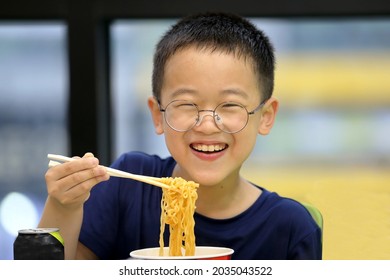 A Child Wearing Black Clothes And Eating Cup Noodles