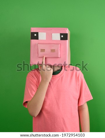 A child is wearing a cardbord pig mask made out of paper for a creative diy craft costume concept.