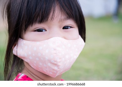 Child Wearing Cloth Face Mask To Prevent Spread Coronavirus (COVID-19) Disease. Closeup Face Girl. In The Public Park. Kid Aged 4-5 Years Old.