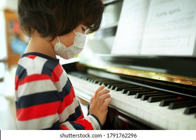 Child wearing face mask playing piano at home.Fingers on keys.Boy having music lesson.Young male musical homeschooling.String instrument.