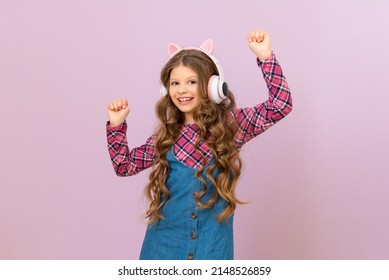 A Child Wearing Headphones On An Isolated Purple Background. A Little Girl Listens To Music.