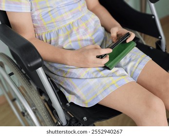 Child in wheelchair engaging with handheld device in indoor setting - Powered by Shutterstock