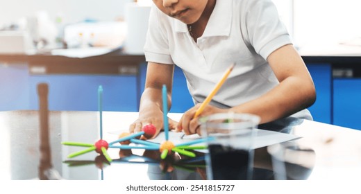 Child in a white shirt building a colorful molecular model in a science classroom. Focused on science, learning, and creativity with a molecular model. Education and knowledge concept. - Powered by Shutterstock