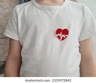 Child In White Shirt With Heart Emblem On Chest. Treatment Of Cardiac Arrhythmia In Children Concept