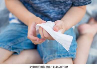 The child wipes his hands with a wet napkin. - Powered by Shutterstock