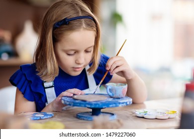 Child working on pottery wheel. Kids arts and crafts class in workshop. Little girl creating cup and bowl of clay. Creative activity in school. - Powered by Shutterstock