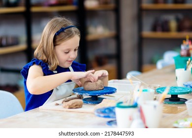 Child working on pottery wheel. Kids arts and crafts class in workshop. Little girl creating cup and bowl of clay. Creative activity for young children in school. Cute kid forming toy with ceramic.  - Powered by Shutterstock