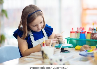 Child working on pottery wheel. Kids arts and crafts class in workshop. Little girl creating cup and bowl of clay. Creative activity for young children in school. Cute kid forming toy with ceramic. 