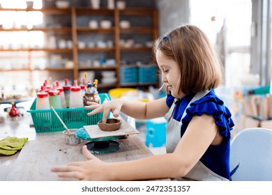 Child working on pottery wheel. Kids arts and crafts class in workshop. Little girl creating cup and bowl of clay. Creative activity for young children in school. Cute kid forming toy with ceramic.  - Powered by Shutterstock