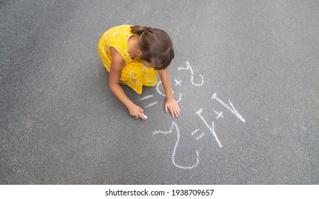 The Child Writes Math On The Pavement. Selective Focus. Summer.