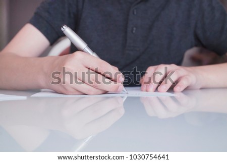 the child writes with a pen on a sheet of paper