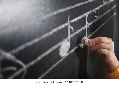 Child Writing Music Notes On Blackboard, Closeup