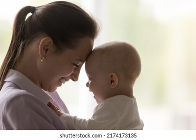 Childcare, Babyhood, Happy Motherhood Concept. Cheerful Baby And Young Laughing Mother Touch Foreheads, Close Up Side Profile View Of Faces, Feeling Love, Enjoy Gentleness And Moments Of Tenderness