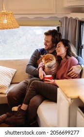 Childfree Married Couple Inside Trailer Or Camper Sit On Cozy Sofa Cuddling Cute Dog Enjoy Weekend Together. Loving Man And Woman Relax In Rv Van On Road Trip On Winter Vacation. Love And Adventure