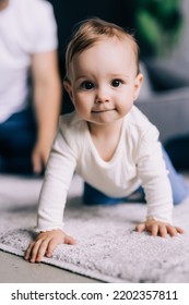 Childhood, Babyhood And People Concept - Happy Little Baby Boy Or Girl Sitting On Floor At Home