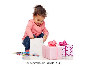 Childhood, Birthday, Party, Holidays And People Concept - Happy Smiling Little African American Baby Girl With Gift Boxes Playing With Confetti And Shopping Bag