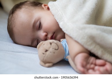 Childhood, Care, Motherhood, Health Concepts - Close Up Little Peace Calm Infant Toddler Baby Girl Sleep Resting Take Deep Nap Laying Hug Teddy Bear Toy On Soft Warm Blanket With Close Eyes On Big Bed