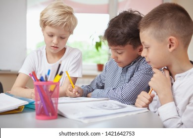 Childhood, Communication Concept. Group Of Little Kids Working On Art Project Together. Two Schoolboys And A Girl Sketching For Art Class Homework