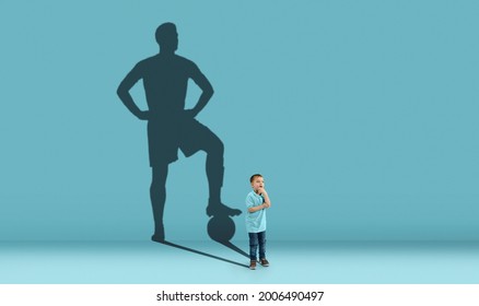 Childhood and dream about big and famous future. Conceptual image with boy and shadow of sportive male football player, champion on blue background. Childhood, dreams, imagination, education concept.